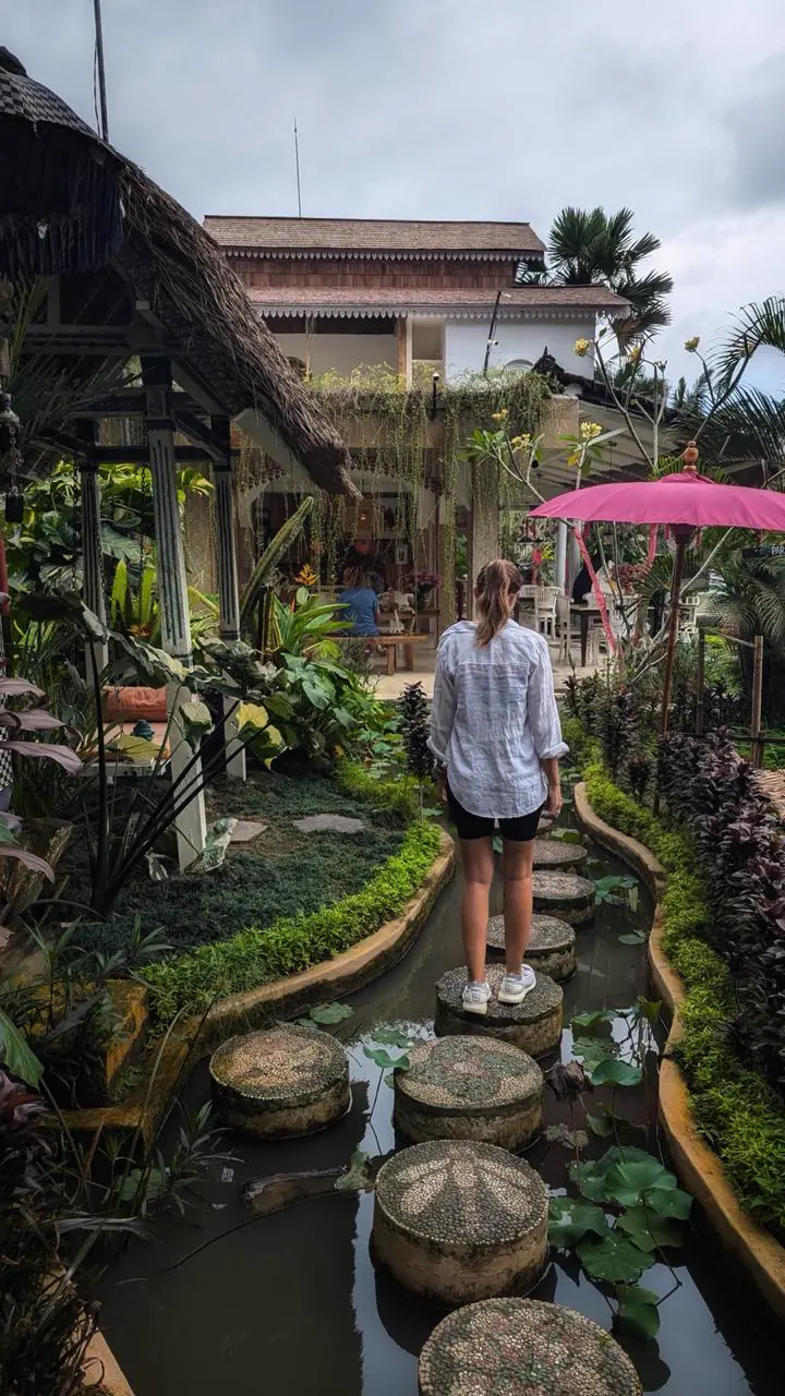 Fiore de espaldas caminando por un jardín con estanque en Bali